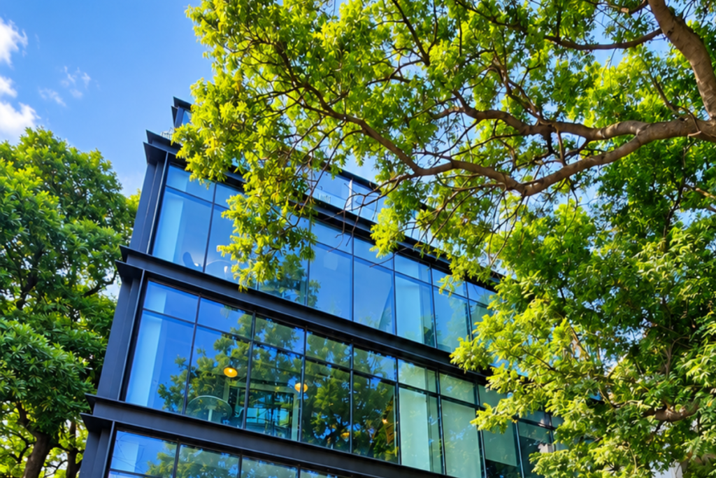 QuickOffice MM Alam building on MM Alam Road, with glass facade and dark steel frames surrounded by green trees